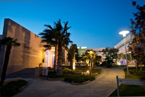 a building with palm trees in front of a building at Regiohotel Manfredi in Manfredonia