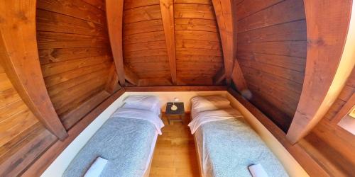 an attic with two beds in a room with wooden walls at Los Altos de Escarrilla - tucasaenlospirineos in Escarrilla