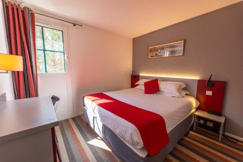a bedroom with a bed with a red and white blanket at Hotel Donibane Saint-Jean-de-Luz in Saint-Jean-de-Luz