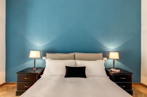 ローマにあるYH SUITE 131の青い壁のベッドルーム1室、ベッド1台(ランプ2つ付)