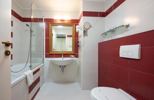 a red and white bathroom with a sink and a toilet at Calimbra Wellness Hotel Superior in Miskolctapolca