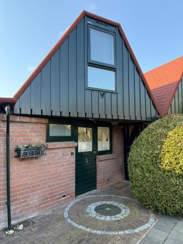 a house with a black roof and a brick wall at Stillwater Lodge De Rijd in Nieuwe-Niedorp
