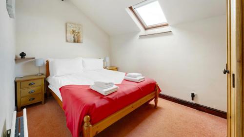 a bedroom with a bed with a red blanket at Sunny Brow Cottage at Thompson Ground in Hawkshead