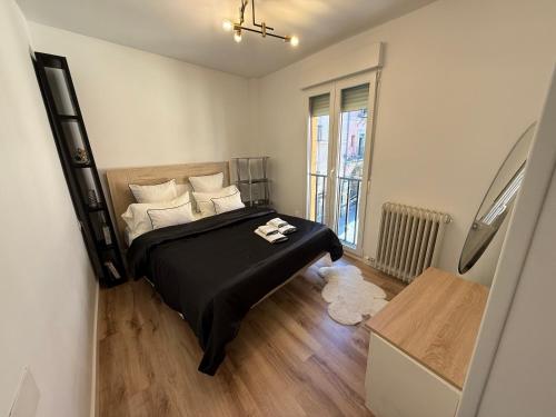 1 dormitorio con 1 cama con sábanas negras y almohadas blancas en Vivienda Plaza Mayor, en León