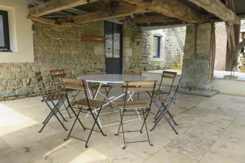 a table and chairs in a room with a stone wall at Le Catalpa in Normier