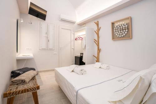a white bedroom with a bed and a chair at Zen Suites & Spa in Perissa