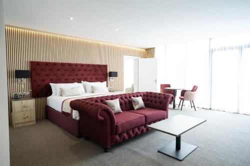 a bedroom with a large bed and a red couch at Dale Hill Hotel in Ticehurst