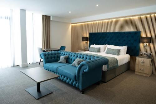a bedroom with a large bed and a blue couch at Dale Hill Hotel in Ticehurst