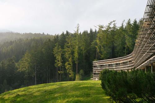 a building on top of a grassy hill with trees at Vigilius Mountain Resort in Lana