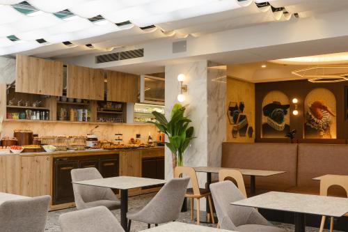 a restaurant with tables and chairs and a kitchen at Hotel Marco Polo in Lido di Jesolo