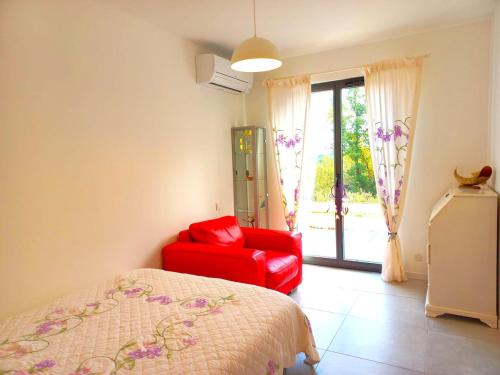 - une chambre avec une chaise rouge, un lit et une fenêtre dans l'établissement Spirit of Provence, à Carsan