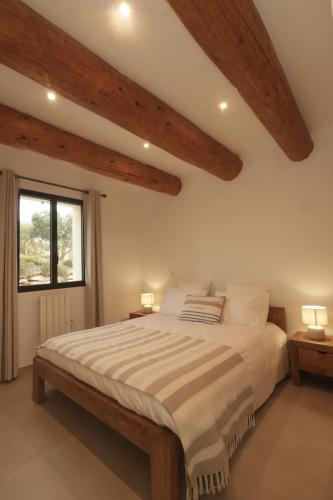 - une chambre avec un grand lit et des poutres apparentes dans l'établissement Les Terrasses de l Oliveraie, à Mireval