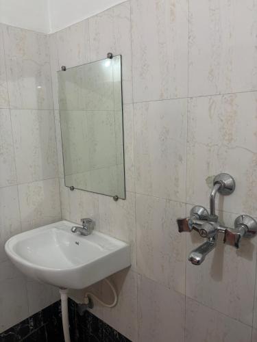 a bathroom with a sink and a mirror on the wall at The Bodhgaya Guest House in Bodh Gaya