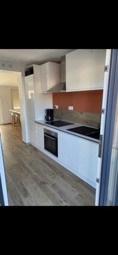 une cuisine avec des armoires blanches et un four à plaques de cuisson dans l'établissement Camiers House, à Camiers