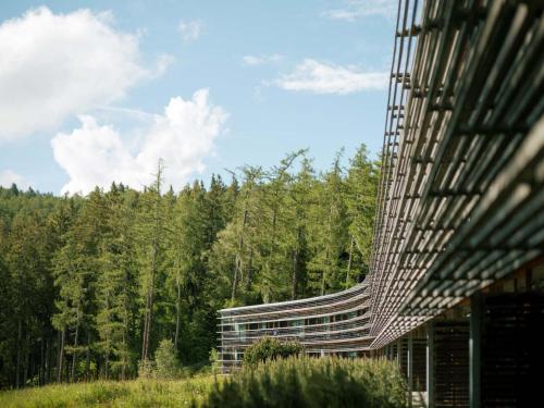 a glass building with a forest in the background at Vigilius Mountain Resort in Lana