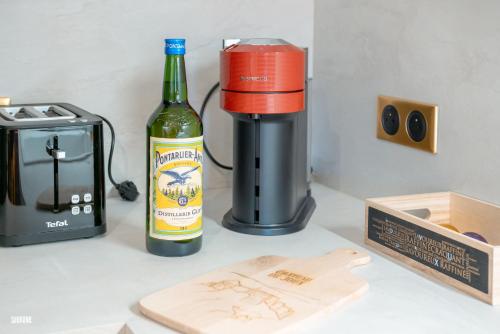 a bottle of wine next to a coffee maker and a bottle of beer at Baignoire Balnéo romantic experience - L'époque in Pontarlier
