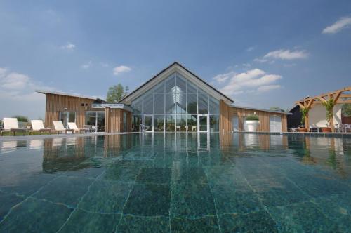 a large swimming pool with a building in the background at 118 Lower Mill Estate - Sleeps 12 Villa with Lake Views in Somerford Keynes