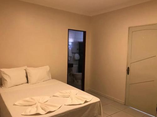 a bedroom with a bed with white sheets and a door at Hotel Prime Ceaka in Caruaru
