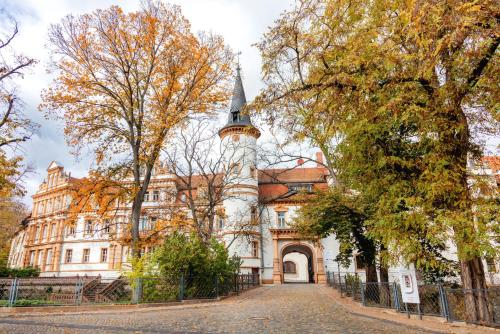 an old building with a clock tower on a street at Hotel Schloss Schkopau in Schkopau