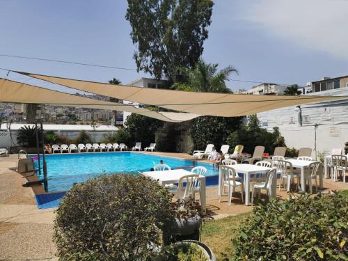 a swimming pool with tables and chairs and a large umbrella at Astoria Galilee Hotel in Tiberias