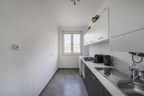 维也纳Perfekte Wohnung für 4 Personen的厨房配有白色橱柜、水槽和窗户