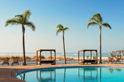 a swimming pool with palm trees and a beach at Tivoli Lagos in Lagos