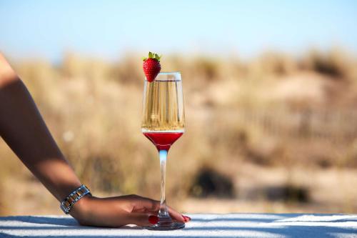a woman holding a glass of wine with a strawberry in it at Tivoli Lagos in Lagos