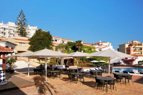 a patio with tables and umbrellas next to a pool at Tivoli Lagos in Lagos