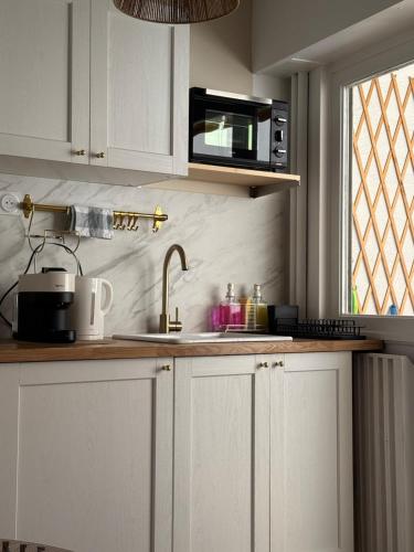 une cuisine avec des armoires blanches, un évier et un micro-ondes dans l'établissement Charming bohemian apartment, à Nice
