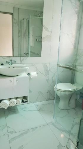 a white bathroom with a toilet and a sink at Rainbow Guest House and Tours in Uitenhage