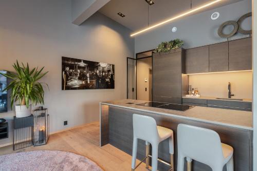 a kitchen with a bar with white stools at Penthouse with fjord view and parking in Sogndal
