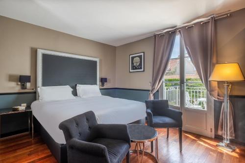 a hotel room with a bed and two chairs and a window at La Villa Mauresque in Saint-Raphaël