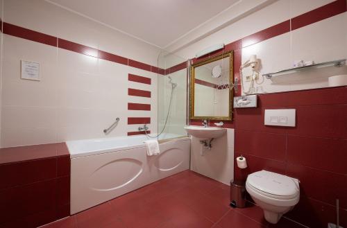 a red and white bathroom with a toilet and a sink at Calimbra Wellness Hotel Superior in Miskolctapolca