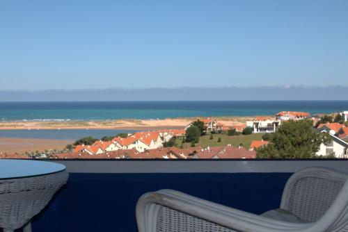 Un balcón con mesa y sillas y el mar. en La Casa Azul con piscina, en Miengo