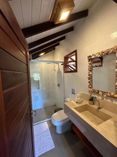 ein Badezimmer mit Toilette, Waschbecken und Spiegel in der Unterkunft Reserva BG - Apto Praiano - Vista mar in Barra Grande