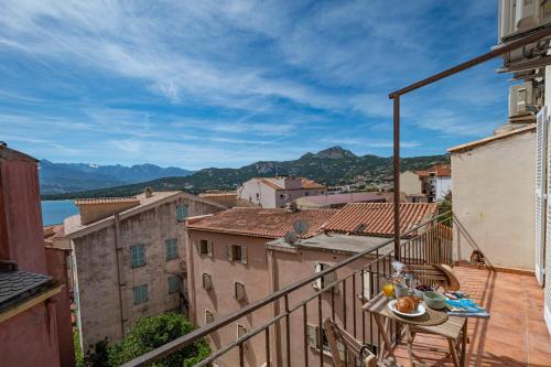 a balcony with a table and a view of a city at Lume appart vue mer au coeur ville à deux pas plage port citadelle in Calvi