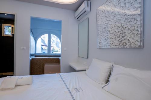 a white bed with white pillows in a room at Zen Suites & Spa in Perissa
