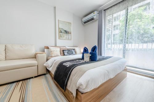 a bedroom with a bed and a couch and a window at Elio Sukhumvit 64 in Bangkok
