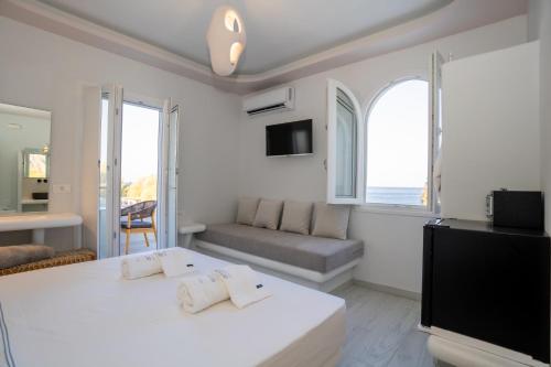 a white bedroom with a large bed and a couch at Zen Suites & Spa in Perissa
