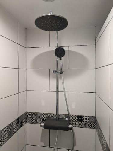 une douche dans une salle de bain avec du carrelage blanc dans l'établissement L'Attellu Di Babbu pour 2, à Lecci