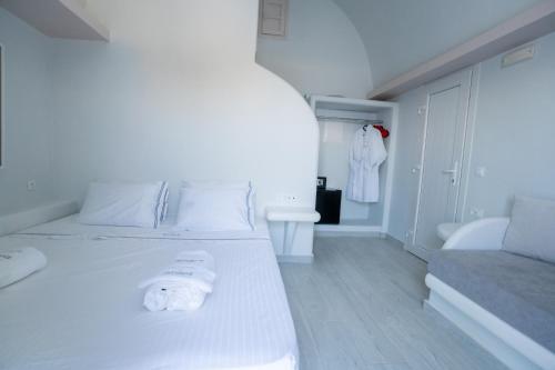 a white bedroom with a white bed and a bathroom at Zen Suites & Spa in Perissa