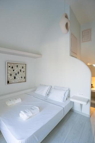 a white bed with two towels on top of it at Zen Suites & Spa in Perissa