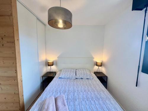 Un dormitorio con una cama con dos lámparas encima. en Le Silène T3 - 4 personnes, en Cluses