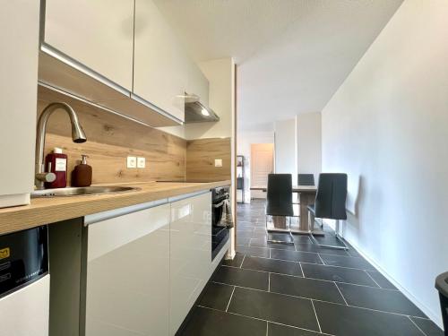 Il comprend une cuisine avec des placards blancs et du carrelage noir au sol. dans l'établissement Le Silène T3 - 4 personnes, à Cluses