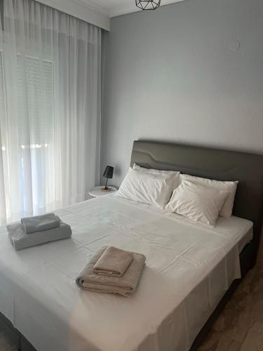 a bedroom with a large white bed with towels on it at Egee Guest House in Néa Péramos
