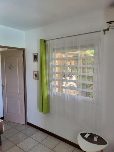 a room with a window with a green curtain at Fleur de canne in Sainte-Rose