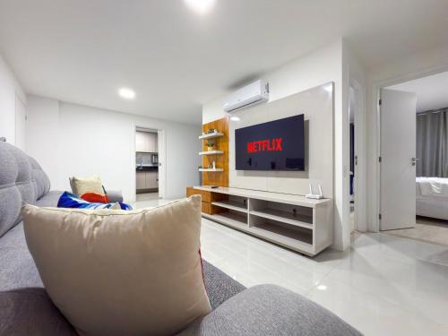 a living room with a couch and a flat screen tv at Apartamento em Arraial do Cabo- Vista Mar, Piscina e Churrasqueira Privativa na Varanda a 50 m da Praia in Arraial do Cabo