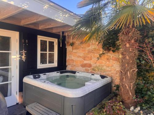 a jacuzzi tub sitting next to a palm tree at Unieke Accommodatie in Twente met Jacuzzi in Borne