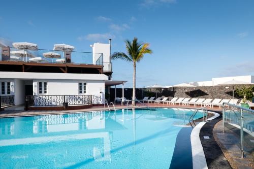 a swimming pool in front of a building at Plus Fariones Apartamentos in Puerto del Carmen