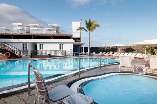 a swimming pool with chairs and a hotel at Plus Fariones Apartamentos in Puerto del Carmen